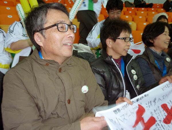 スタンドから応援する小平奈緒選手の父安彦さん（左）と母光子さん（中央）（2014年2月、写真：共同通信社）