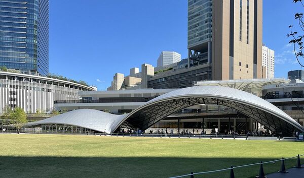 「グラングリーン大阪」にある「うめきた公園」の大屋根施設。公園と一体に使われる半屋外の広場と、インフォメーション、カフェが収められている。「グラングリーン大阪」設計：日建設計、三菱地所設計、大林組、竹中工務店、SANAA、GGN（写真：倉方俊輔）