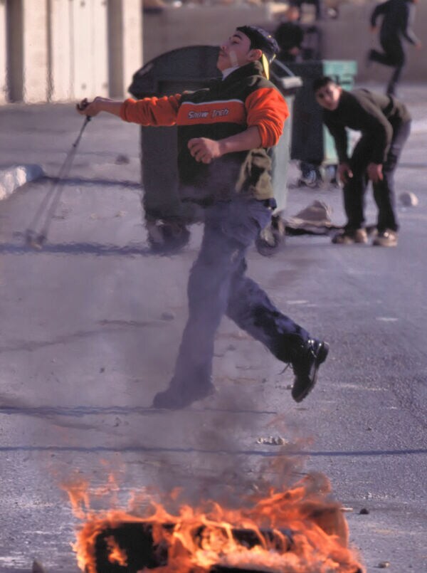 イスラエル軍へ投石で抵抗する青年。ヨルダン川西岸ジェニンにて