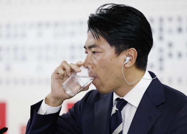 メディアのインタビューの合間に水を飲む自民党の小泉選対委員長＝27日午後8時24分、東京・永田町の党本部