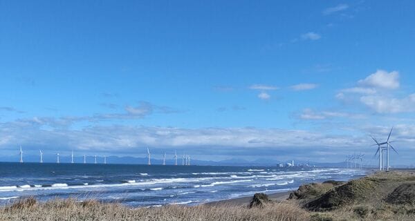 【写真2】石狩湾に建設された14基の洋上風力発電所（画面左）。中央右の遠景に石狩湾新港火力発電所、右側に陸上の風力発電所も見える。「おたるドリームビーチ」から筆者撮影