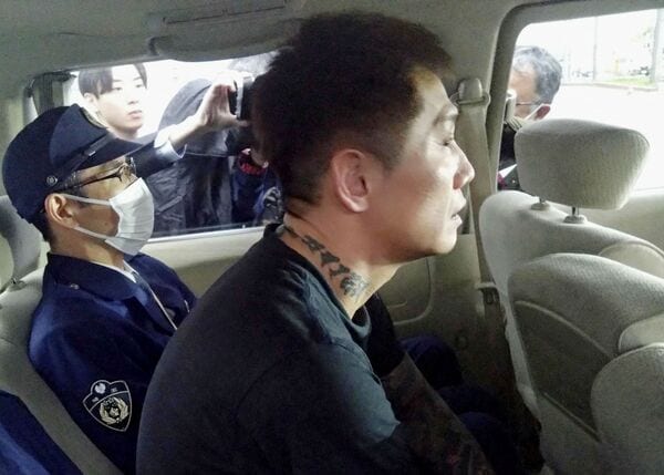 送検される西村容疑者。視線の先には何が移っているのだろうか(写真:共同通信社)